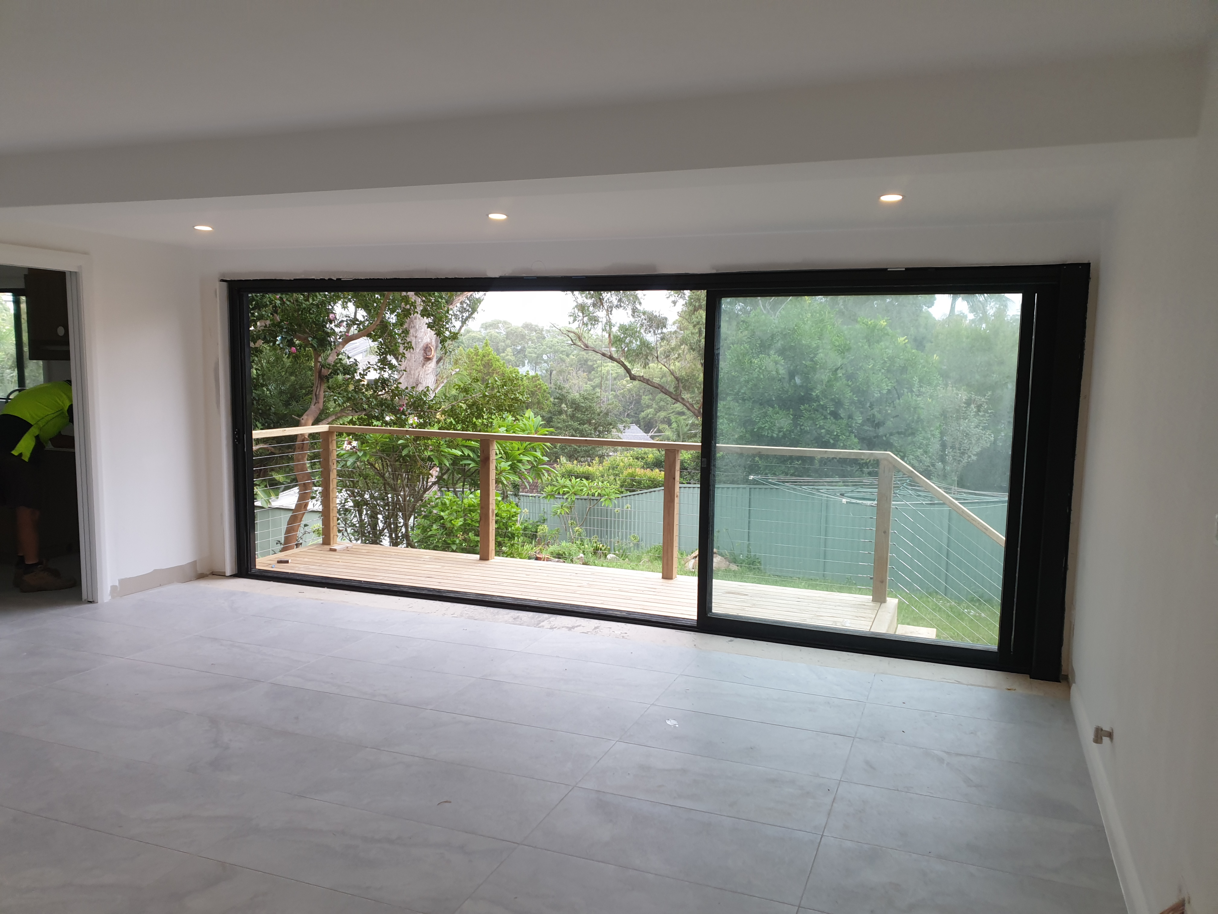 Modern home interior looking out through wide open bifold doors to a patio, demonstrating seamless indoor-outdoor living without visible screens
