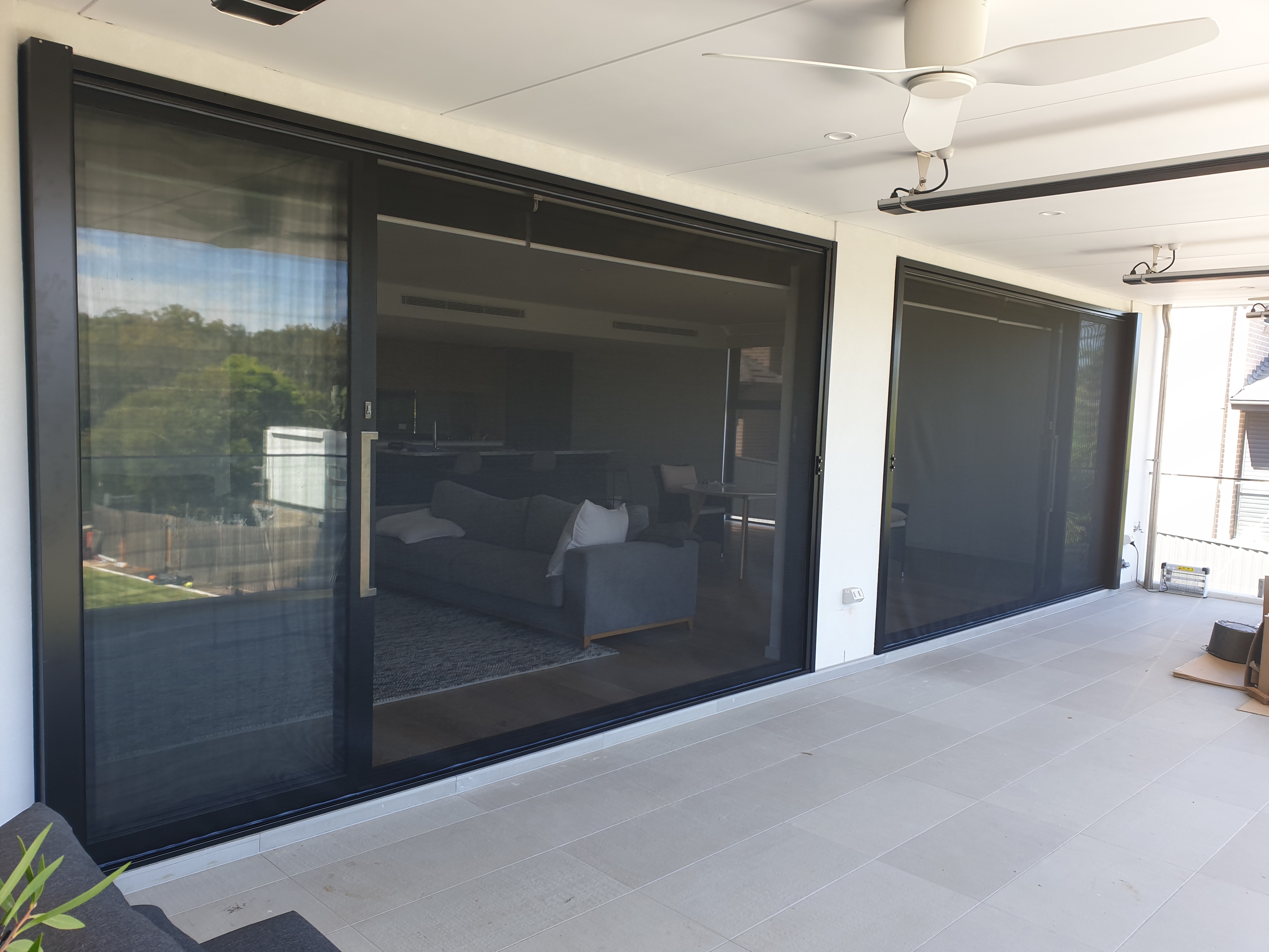 Large motorized retractable screen being deployed over a wide alfresco outdoor entertaining area
