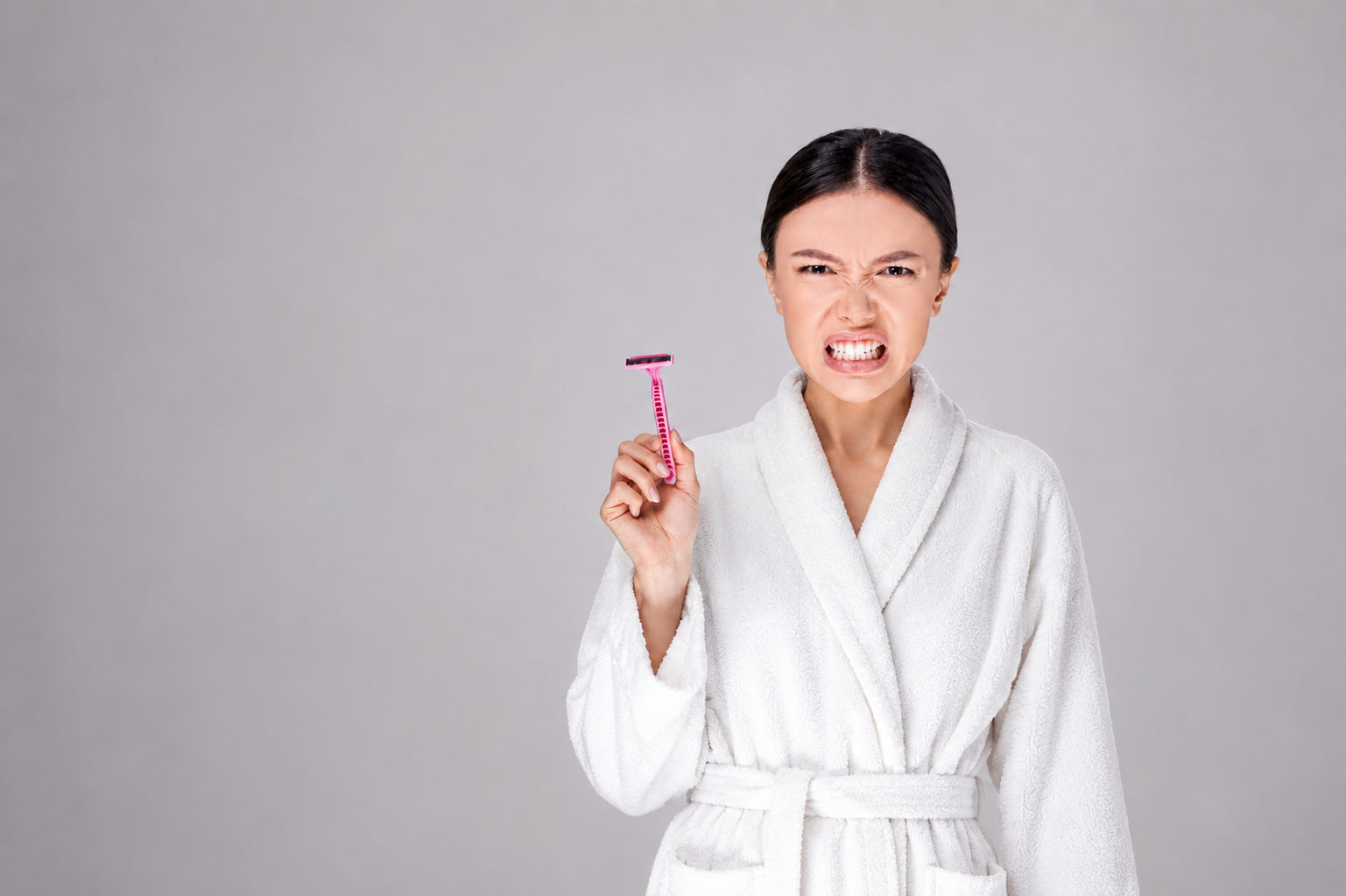 Aesthetic clean flat-lay of a generic razor being thrown into a stylish modern waste bin on crisp white background
