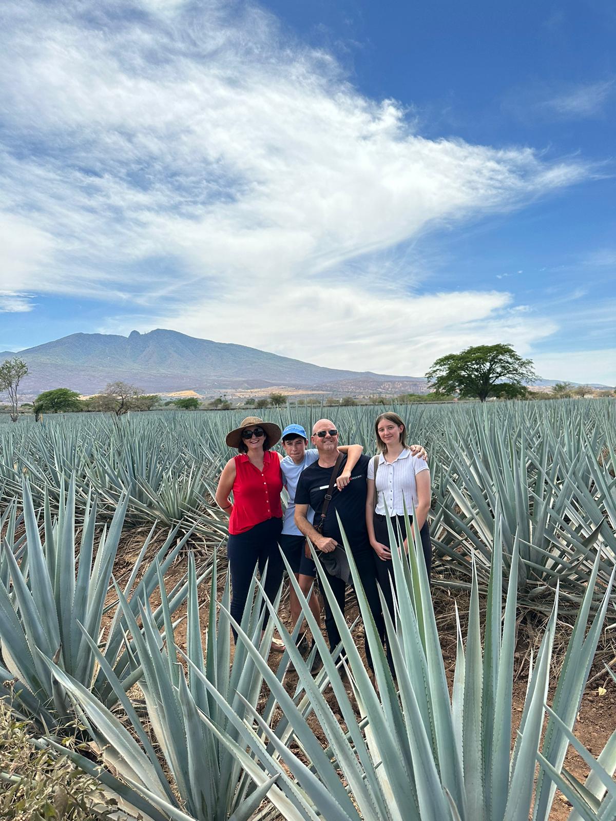 A smiling family standing together outside a welcoming home on their travels