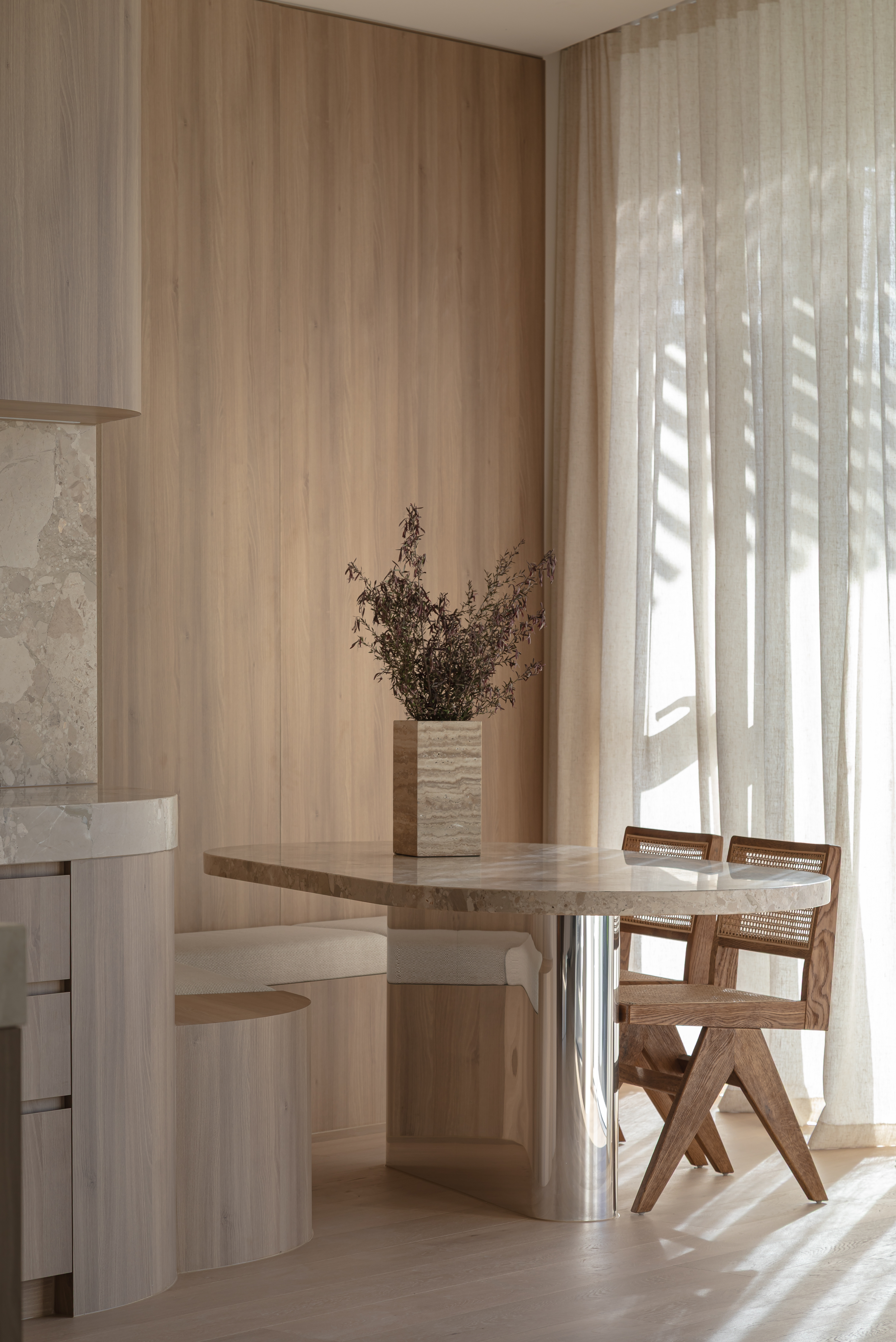 Neutral toned lounge room with boucle armchair, woven rug and sheer curtains filtering daylight