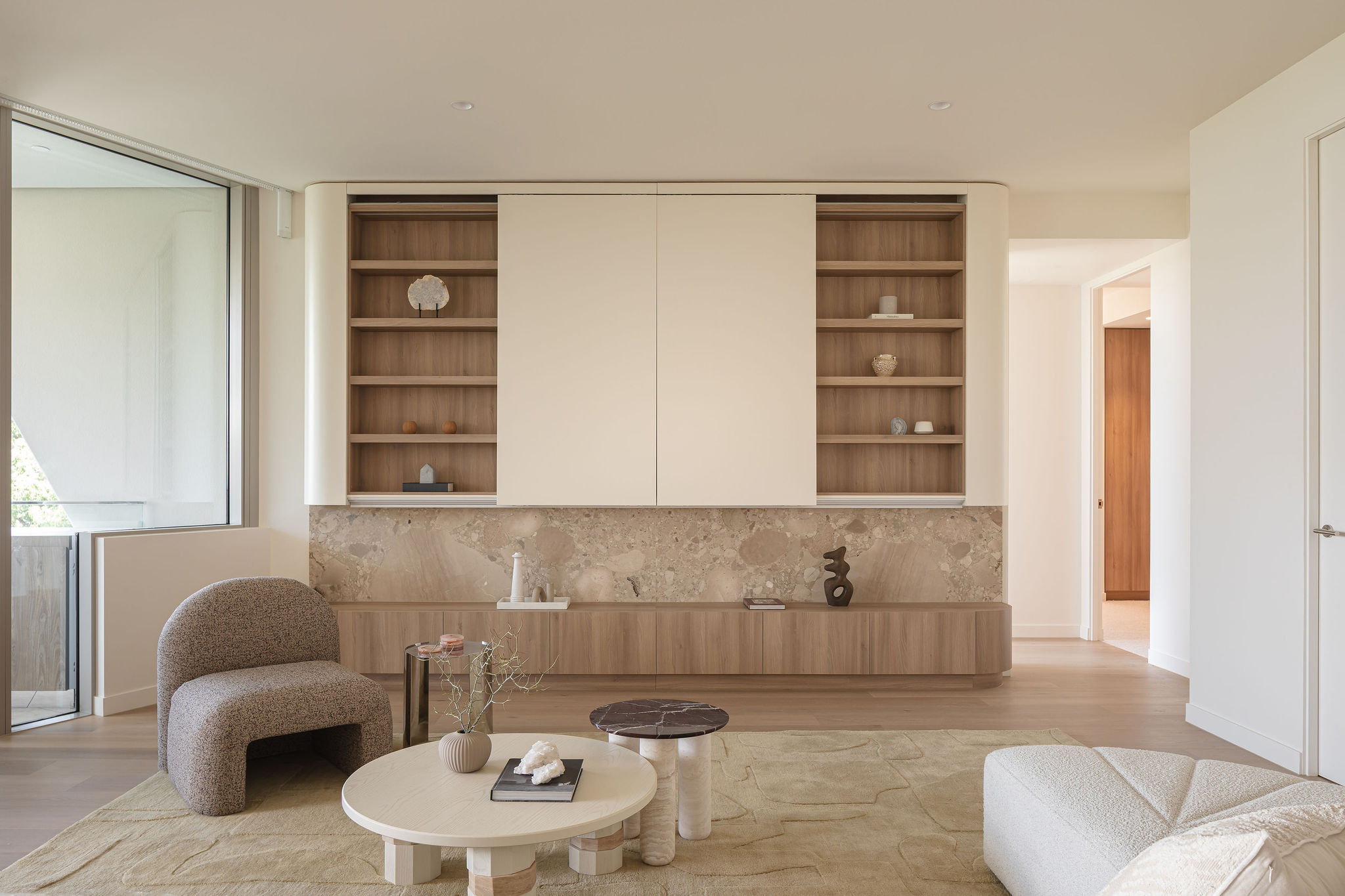 Modern kitchen and breakfast bar with stone benchtop, timber stools and styled ceramic accessories